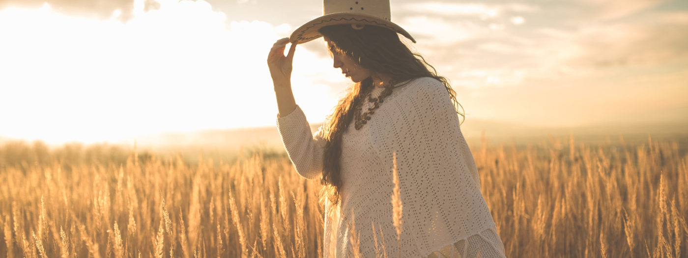 Girl walking into the sunset in a field