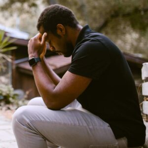 man sitting outdoors with head in hands
