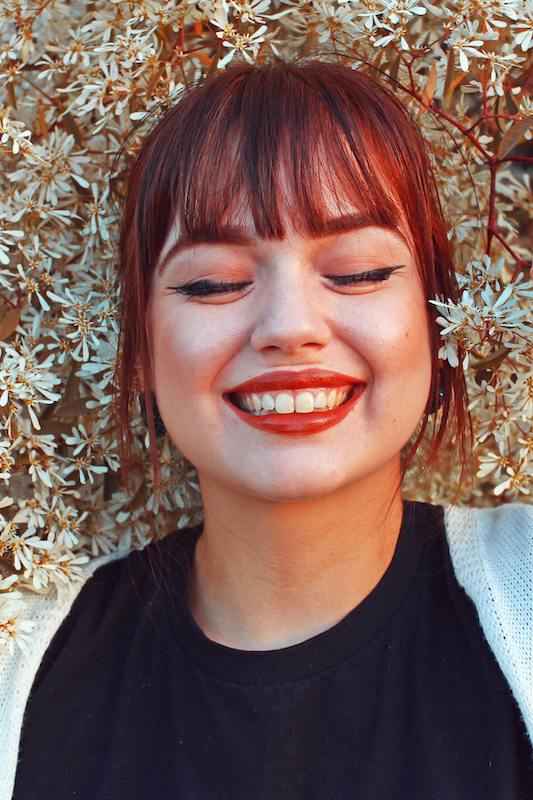 woman with head in flowers smiling