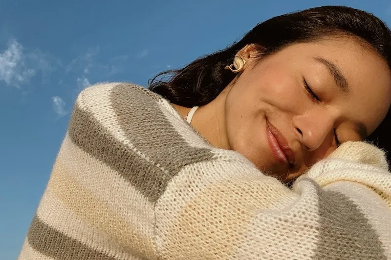 young woman with head on shoulder smiling