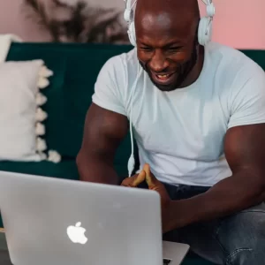 man using laptop with headphones smiling