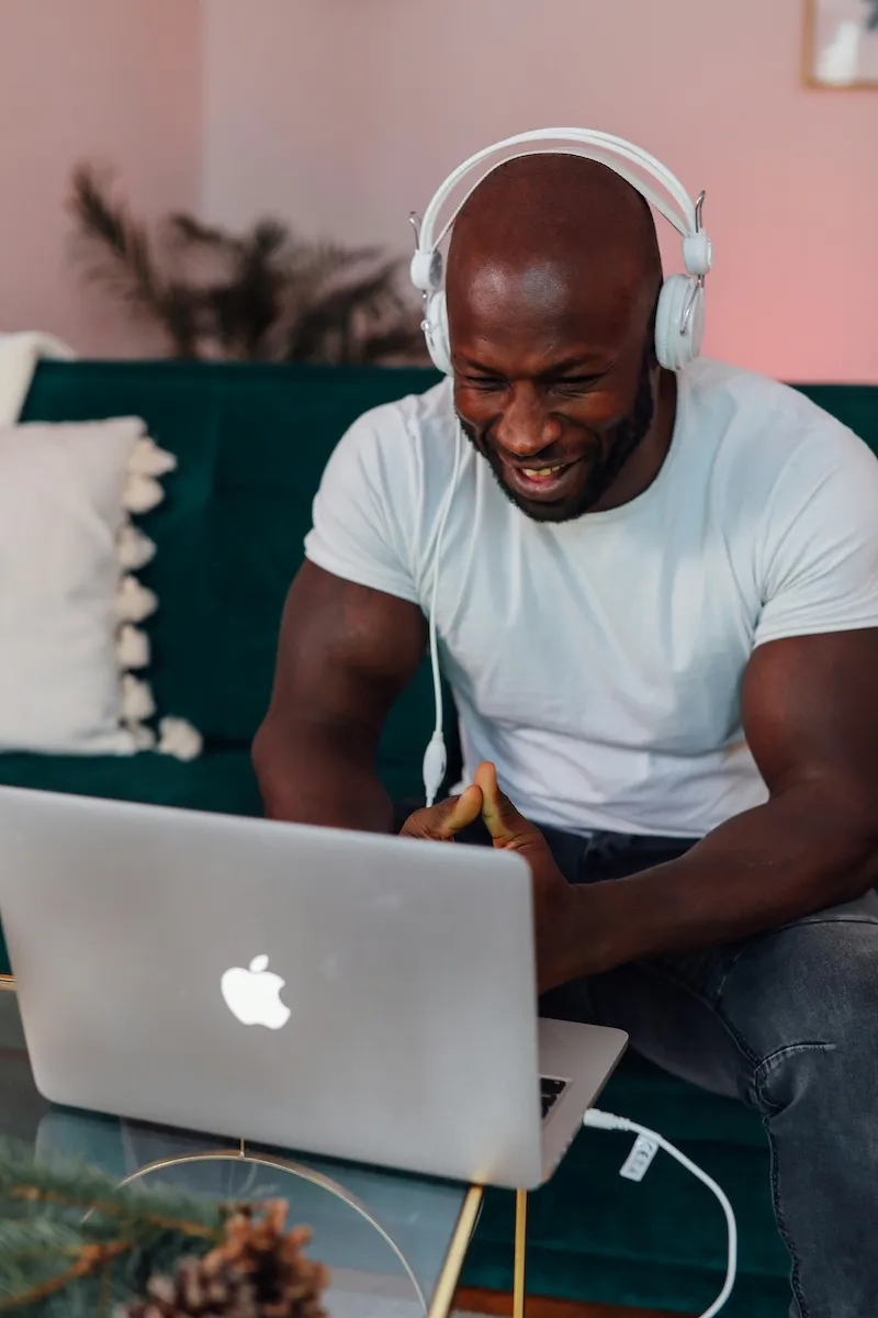 man using laptop with headphones smiling