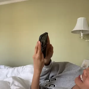 woman laying in bed scrolling on phone