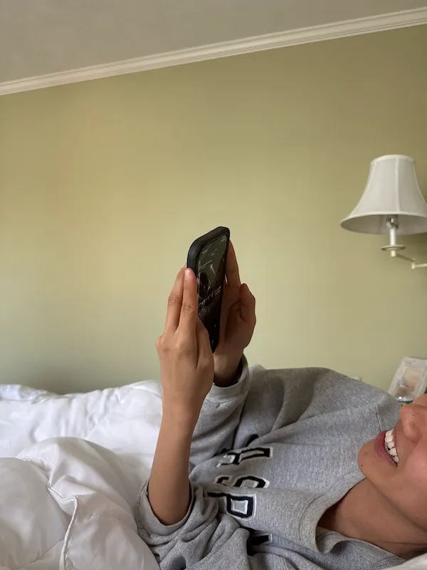 woman laying in bed scrolling on phone