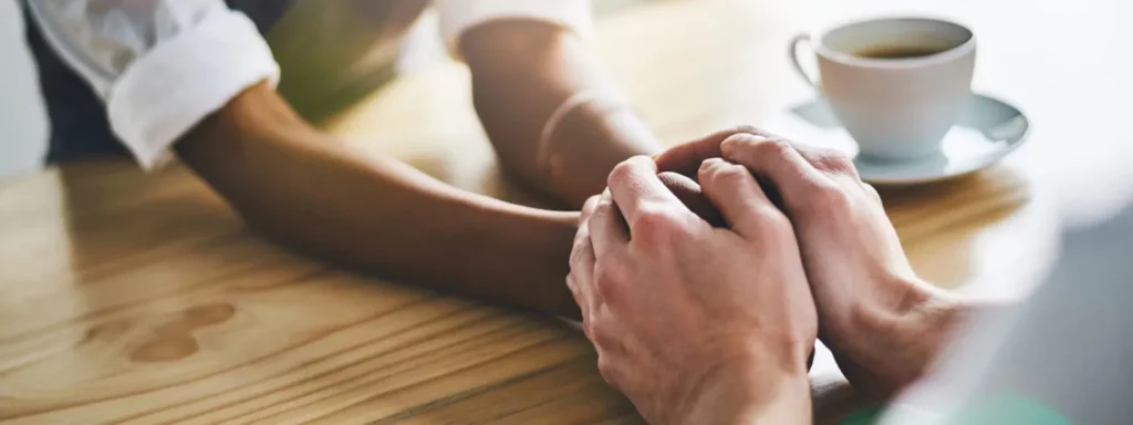people holding hands across table in support