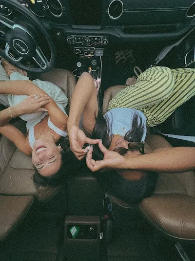 two women laughing together in car front seat