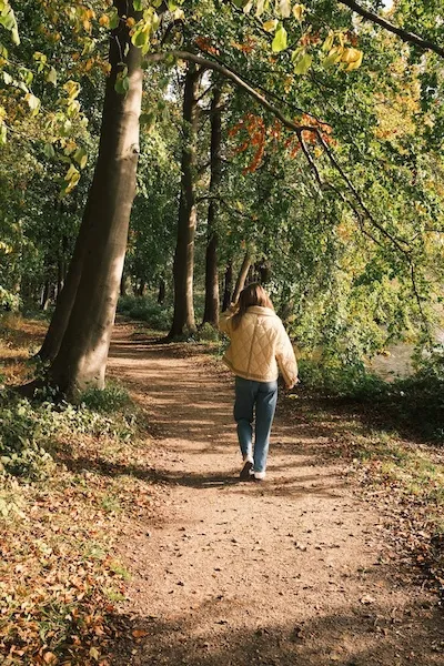 woman walking through trees alone