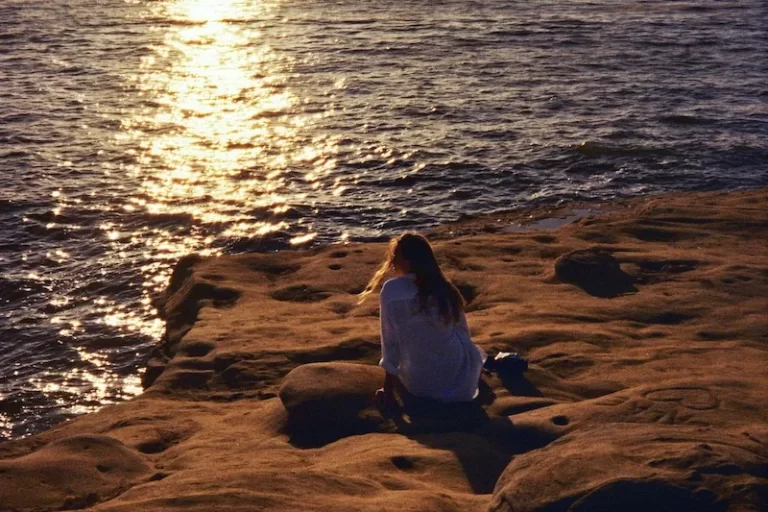 woman sitting on rock looking over ocean