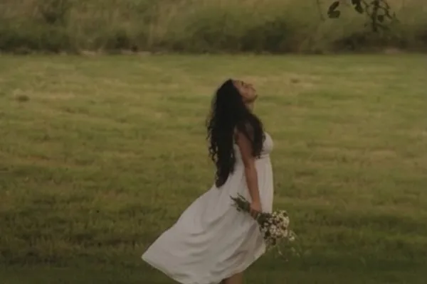 woman standing outdoors in field wearing white dress